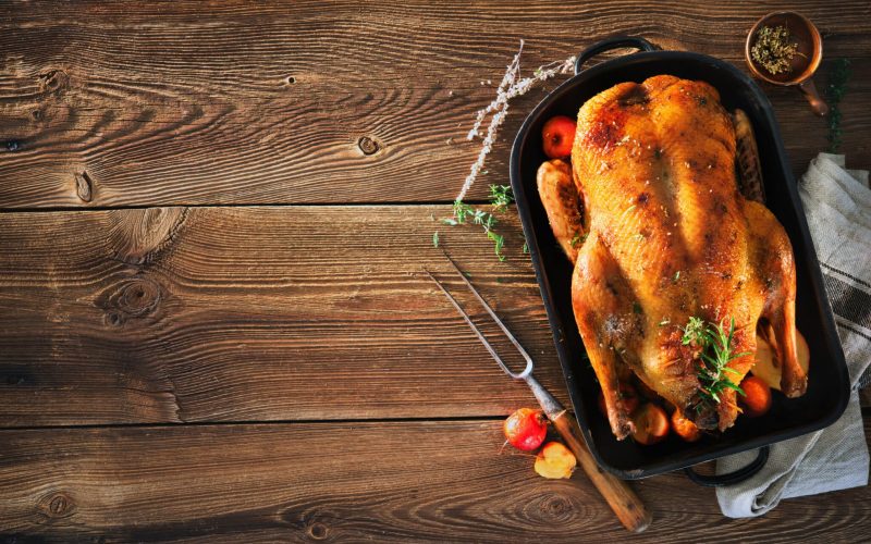 Roast Christmas duck with thyme and apples on rustic wooden table